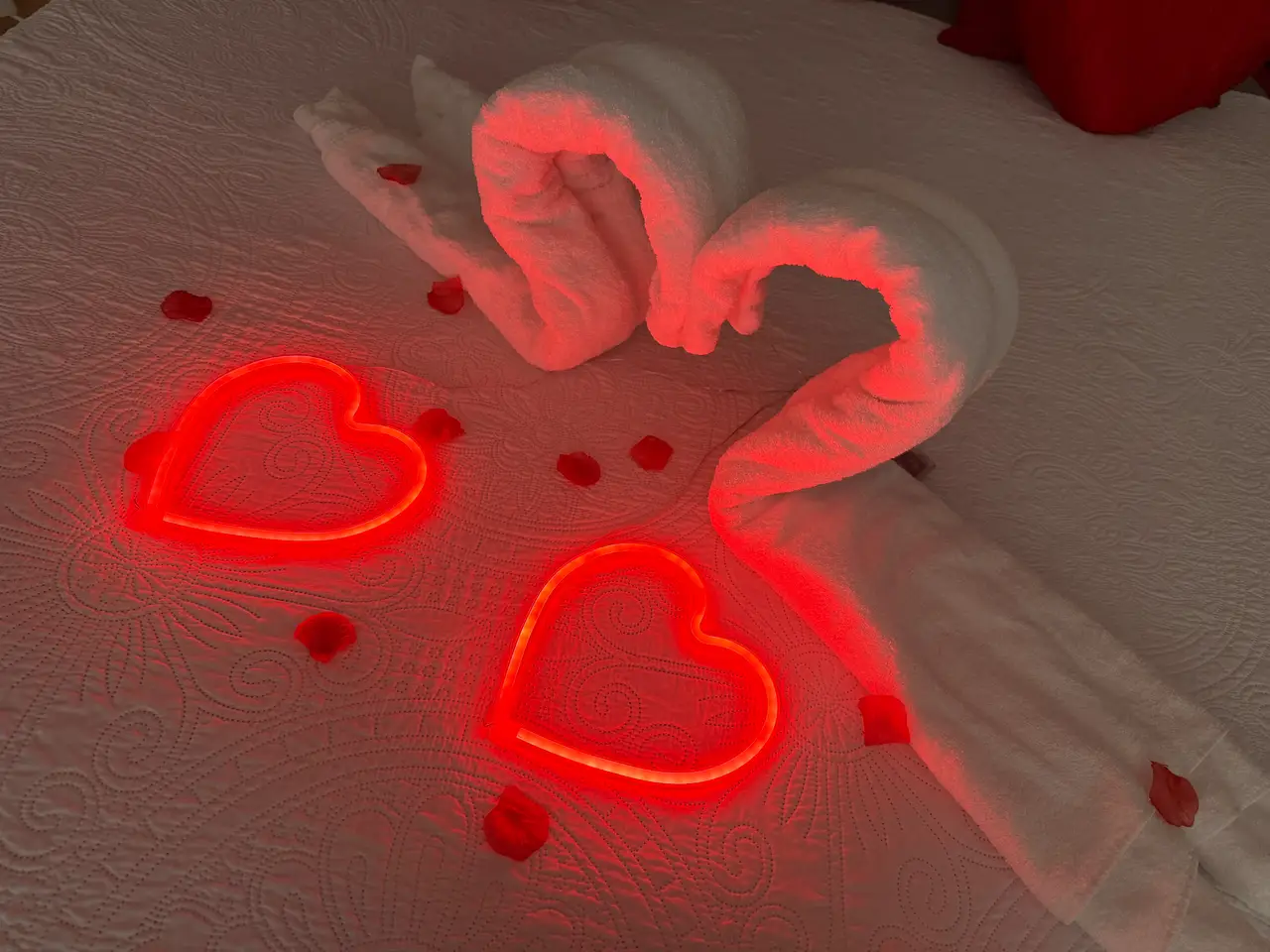 Liebevolles Detail der Privat Spa Suite: Handtuch-Schwäne in Herzform, zwei leuchtende rote LED-Herzen und zarte Rosenblätter – perfekt für romantische Anlässe und Überraschungen.