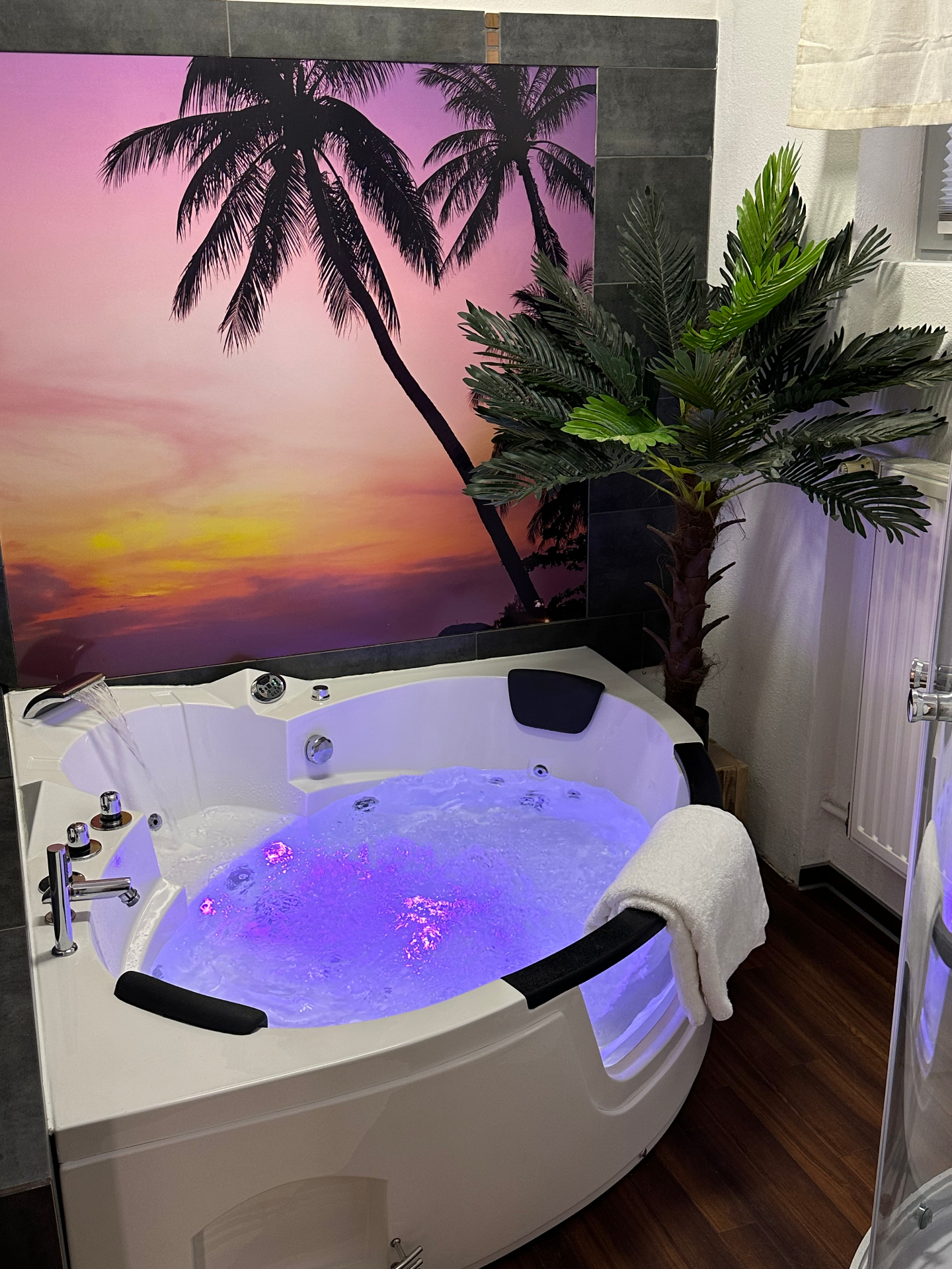 Großer Whirlpool mit LED-Lichttherapie und Palmenmotiv in der Private Spa Suite