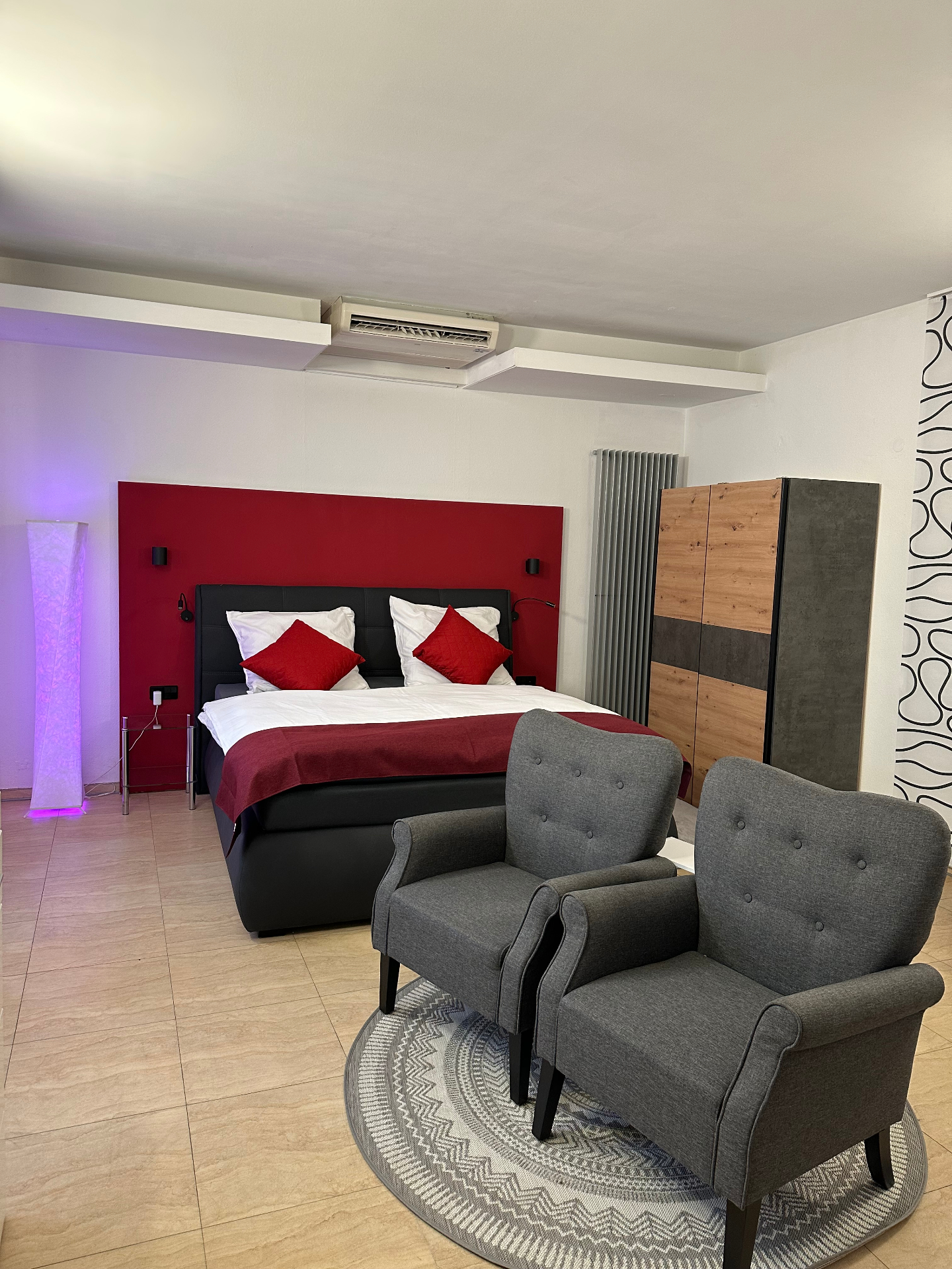 Wohn- und Schlafbereich mit Doppelbett, Sesseln und stimmungsvoller Beleuchtung