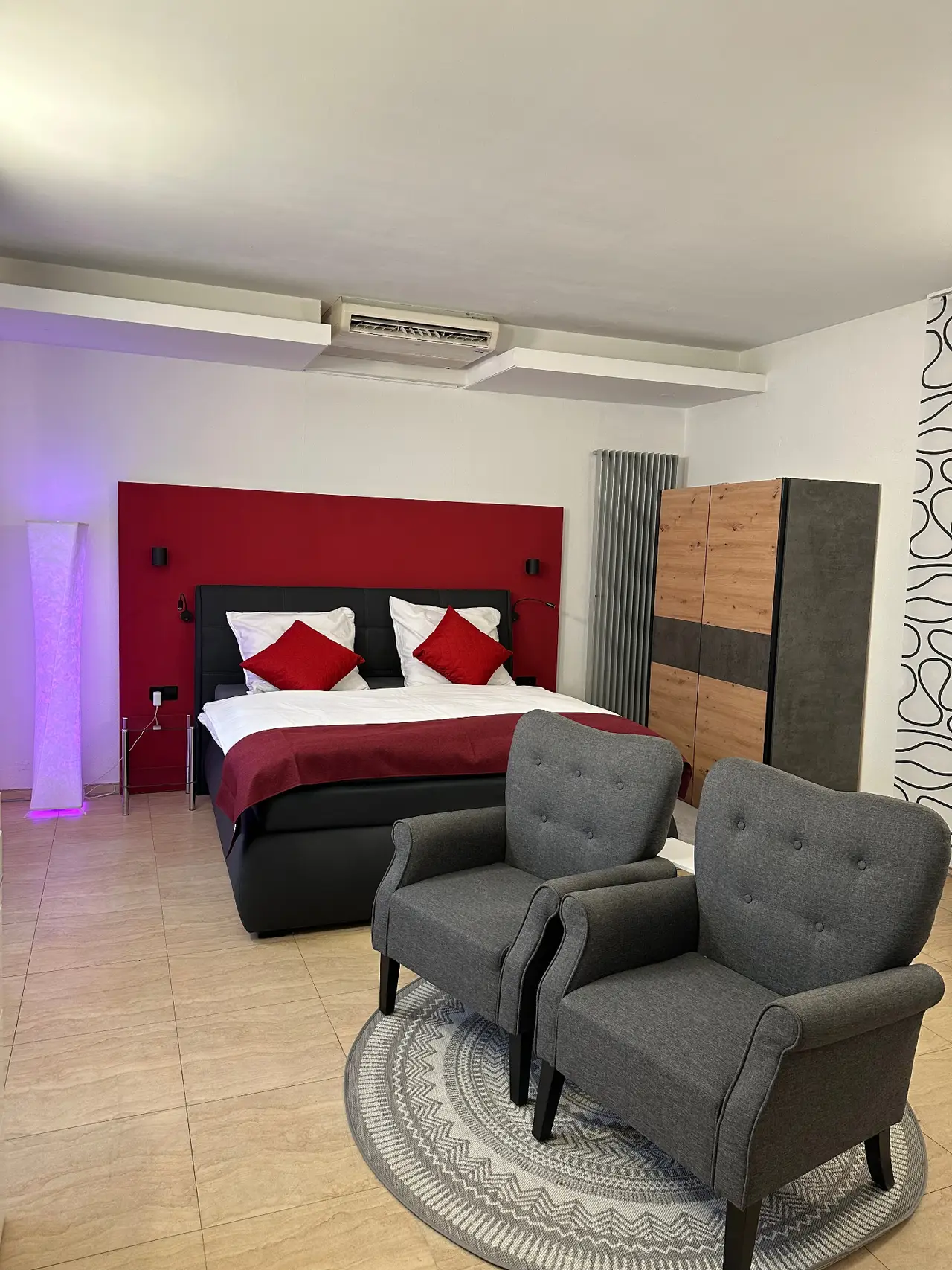 Wohn- und Schlafbereich mit Doppelbett, Sesseln und stimmungsvoller Beleuchtung